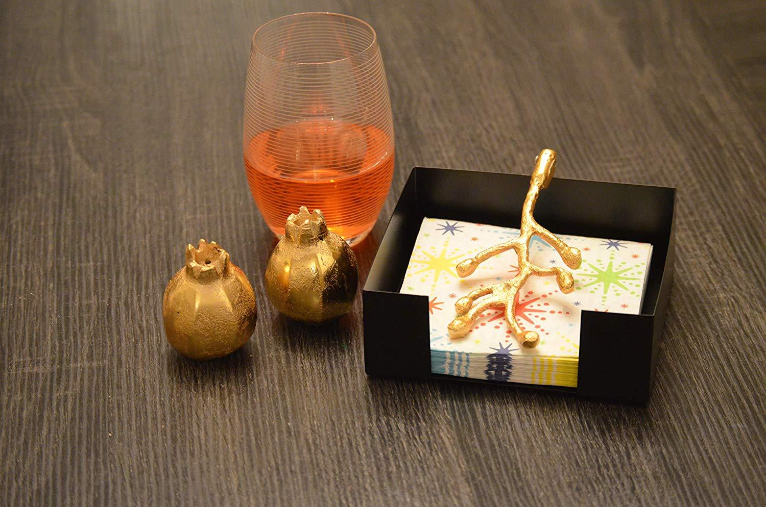 Handcrafted golden napkin holder with olive bud design and unique pomegranate salt and pepper shakers, elegantly displayed on a dining table.