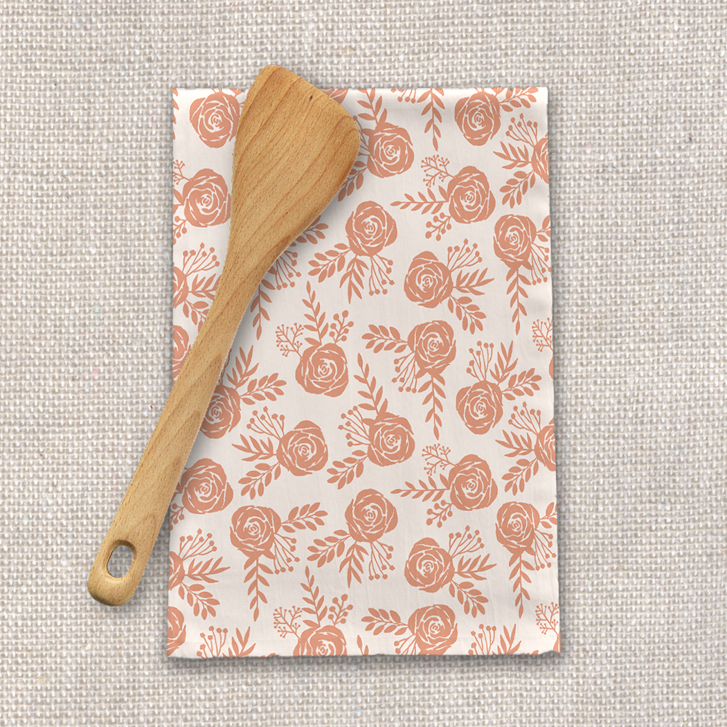 Warm orange floral tea towel made of cotton twill, featuring a vibrant floral design and hemmed edges, perfect for kitchen use.