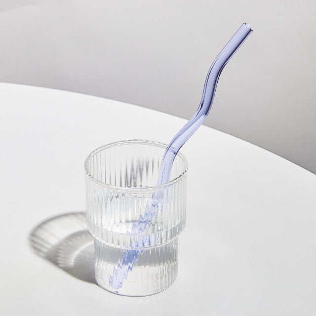 A set of elegant wavy glass straws in various colors, showcasing their unique curved design and included cleaning brush.