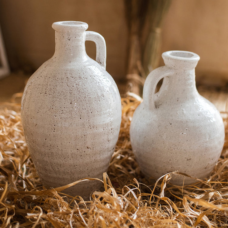 A beautifully crafted white ceramic vase with a small opening, showcasing a textured finish and unique handmade details.