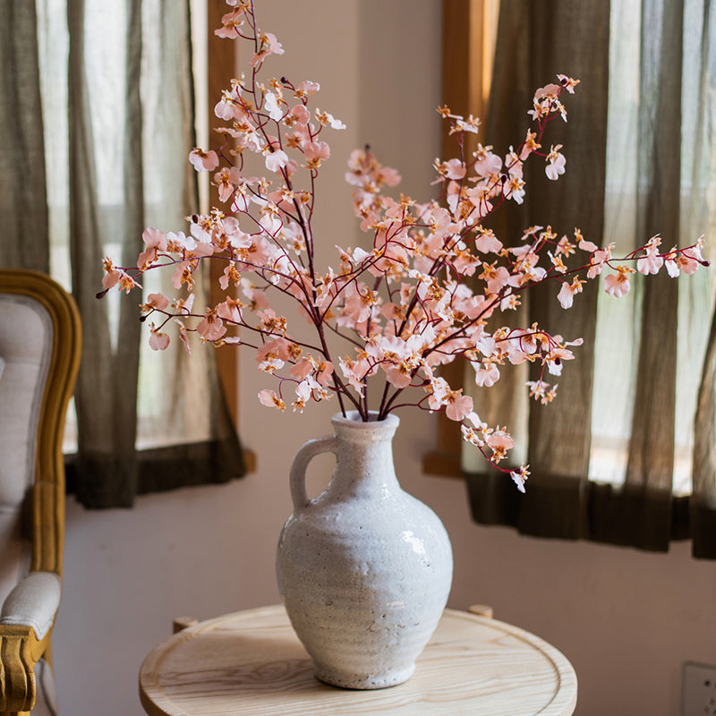 A beautifully crafted white ceramic vase with a small opening, showcasing a textured finish and unique handmade details.