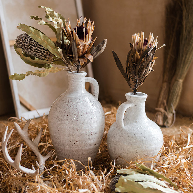 A beautifully crafted white ceramic vase with a small opening, showcasing a textured finish and unique handmade details.