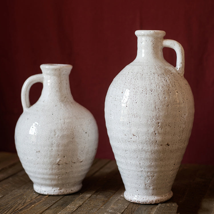 A beautifully crafted white ceramic vase with a small opening, showcasing a textured finish and unique handmade details.