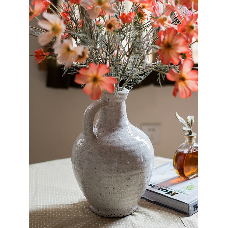 A beautifully crafted white ceramic vase with a small opening, showcasing a textured finish and unique handmade details.