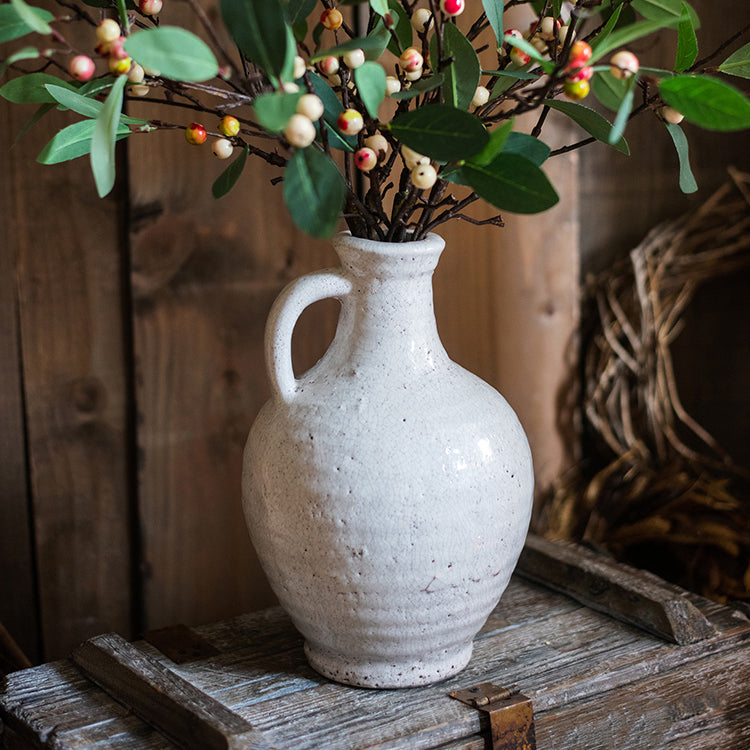 A beautifully crafted white ceramic vase with a small opening, showcasing a textured finish and unique handmade details.