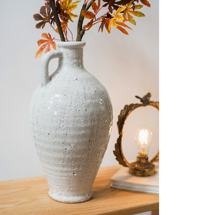 A beautifully crafted white ceramic vase with a small opening, showcasing a textured finish and unique handmade details.