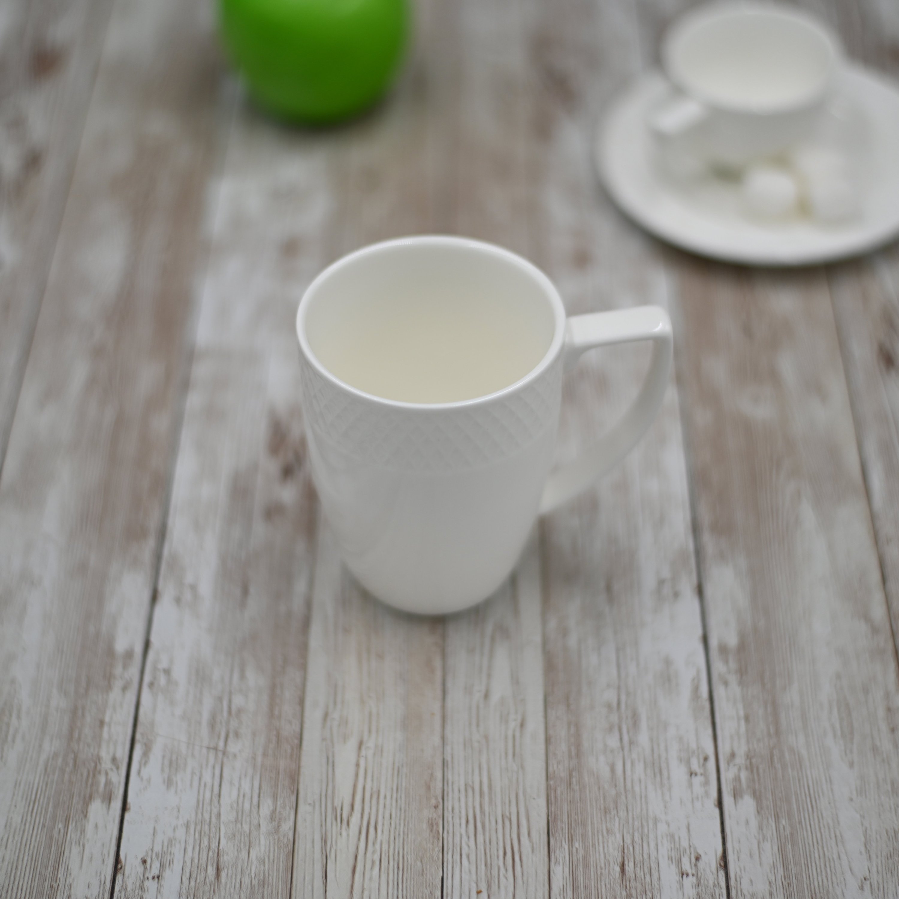 A stylish WILMAX white coffee mug with an embossed design, perfect for serving coffee or tea, showcasing its elegant rolled rim and durable porcelain material.