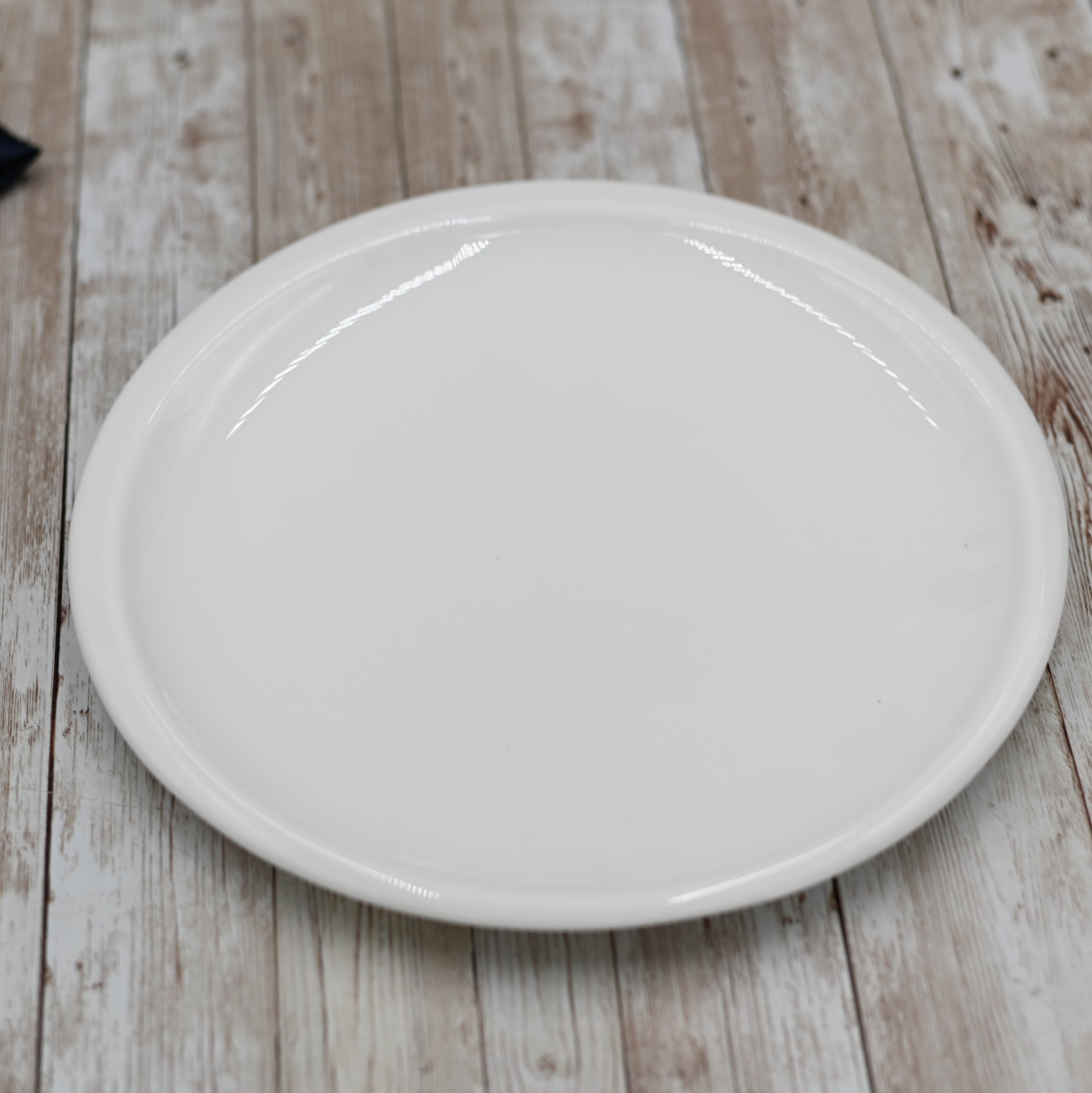 A pristine white 9.5-inch dinner plate made of durable porcelain, showcasing an elegant rolled rim design, perfect for any dining occasion.