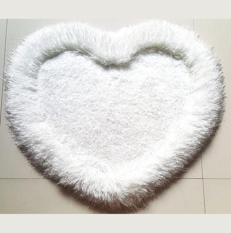 A soft and plush white heart-shaped area rug measuring 28" x 32", perfect for adding a decorative touch to any room.