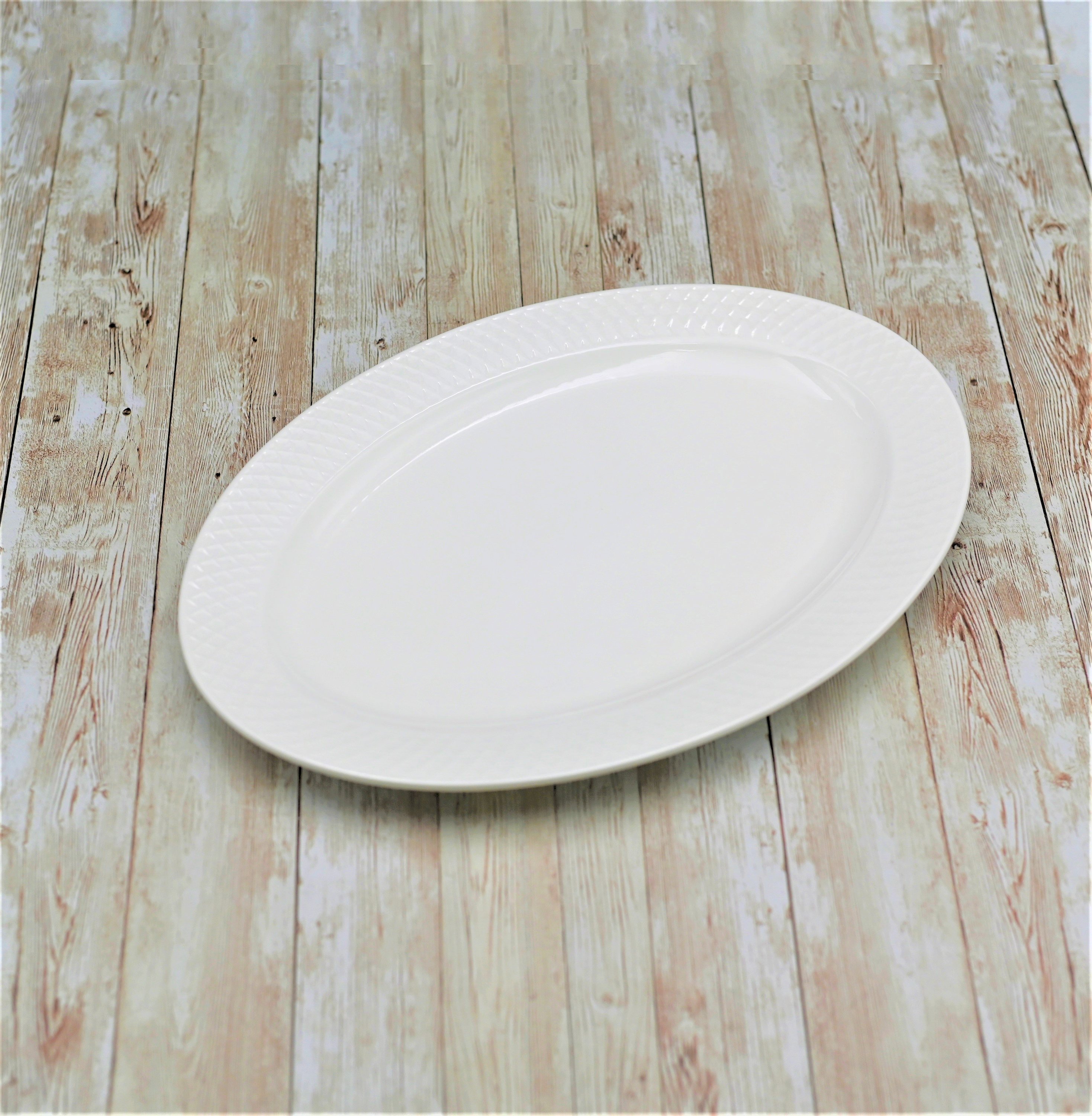 Elegant white oval platter with embossed wide rim, perfect for serving various dishes.