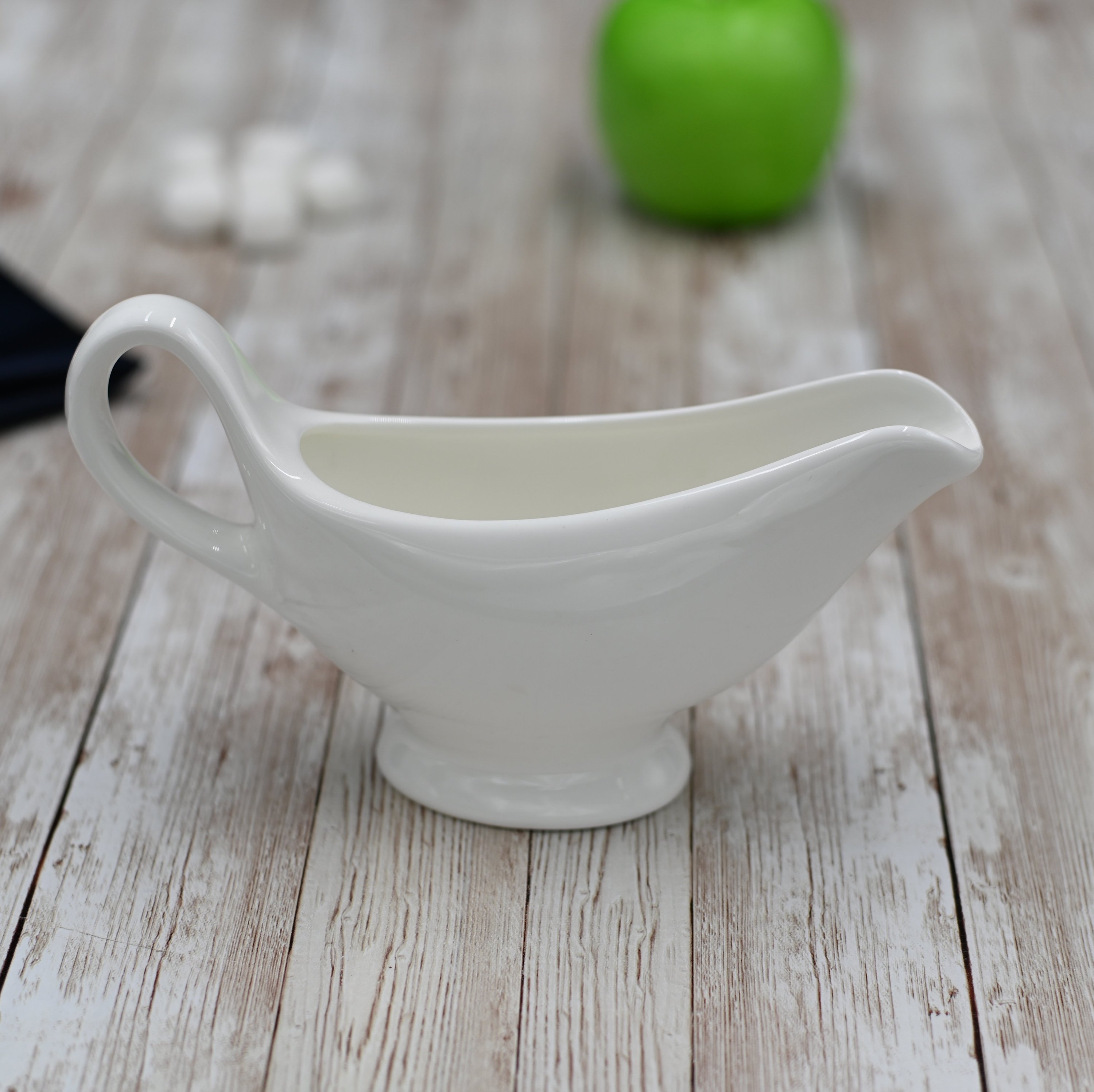 Elegant white porcelain sauce boat with handle, 6 oz capacity, perfect for serving sauces and gravies.