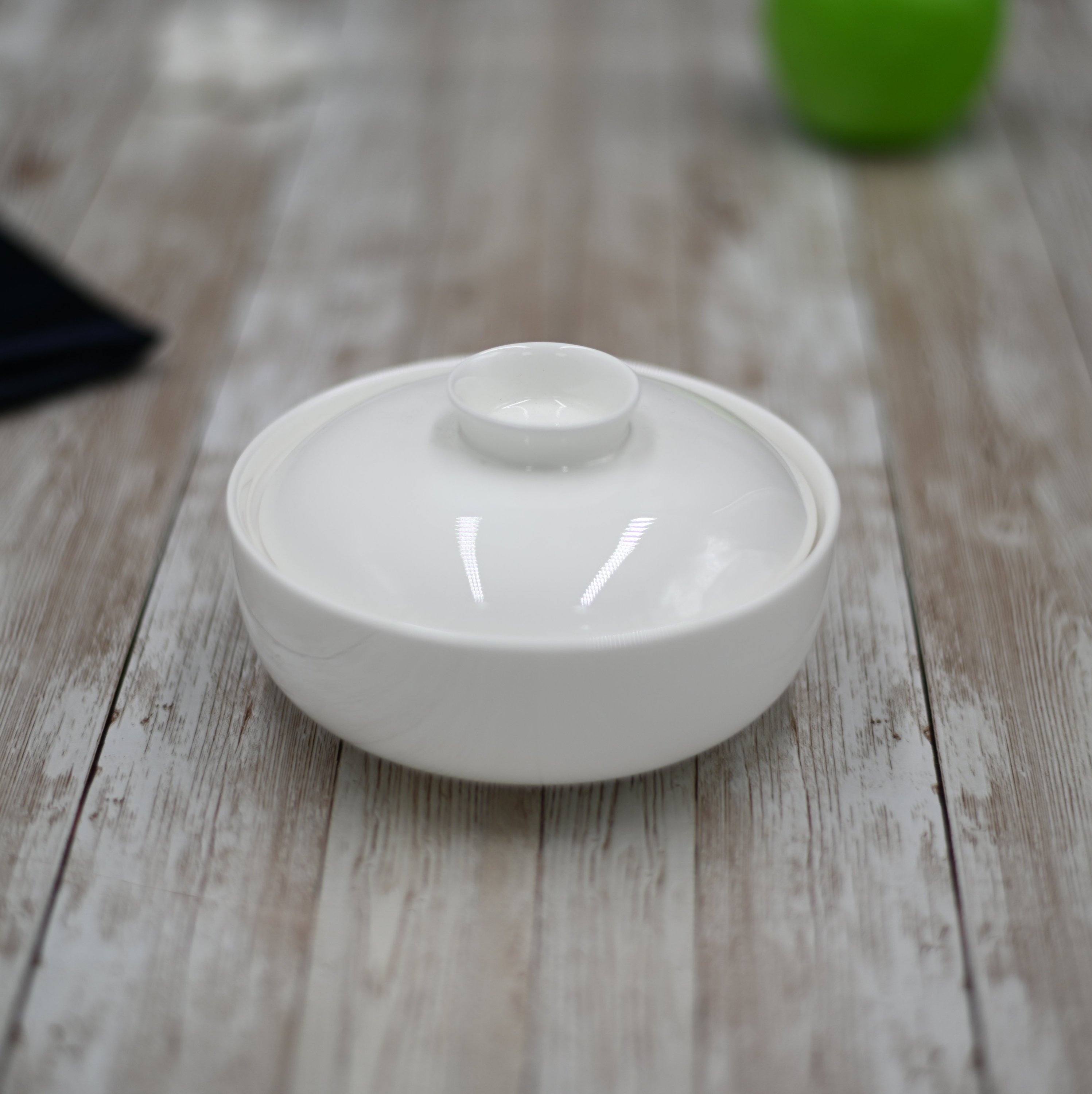 A 5-inch white porcelain soup cup with a lid, ideal for serving soups and stews, showcasing its elegant design and stackable feature.