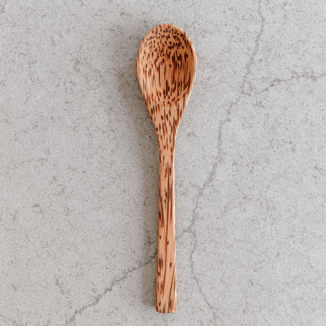 A beautifully handcrafted Wooden Coconut Spoon made from natural coconut shell, showcasing its unique grain and smooth finish.