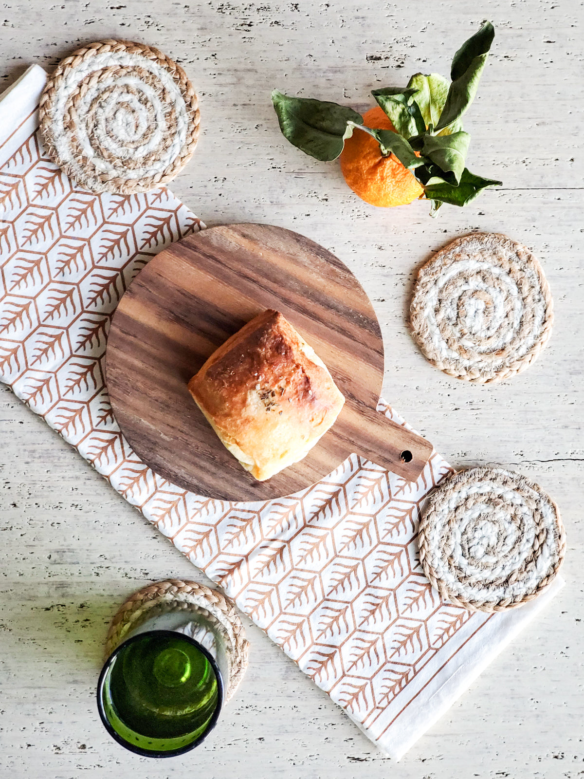 Handcrafted Wooden Round Serving Board with a hand screen-printed tea towel, showcasing natural wood grain and artisan design.