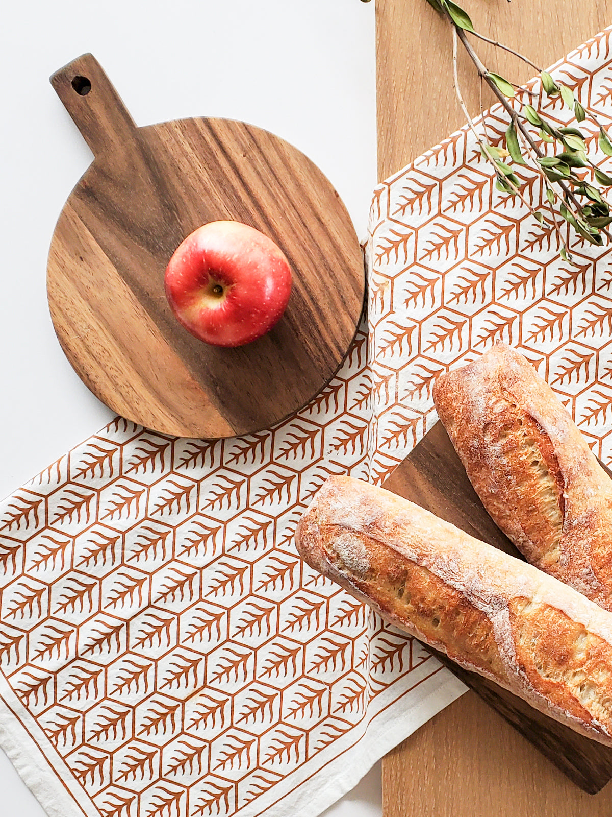 Handcrafted Wooden Round Serving Board with a hand screen-printed tea towel, showcasing natural wood grain and artisan design.