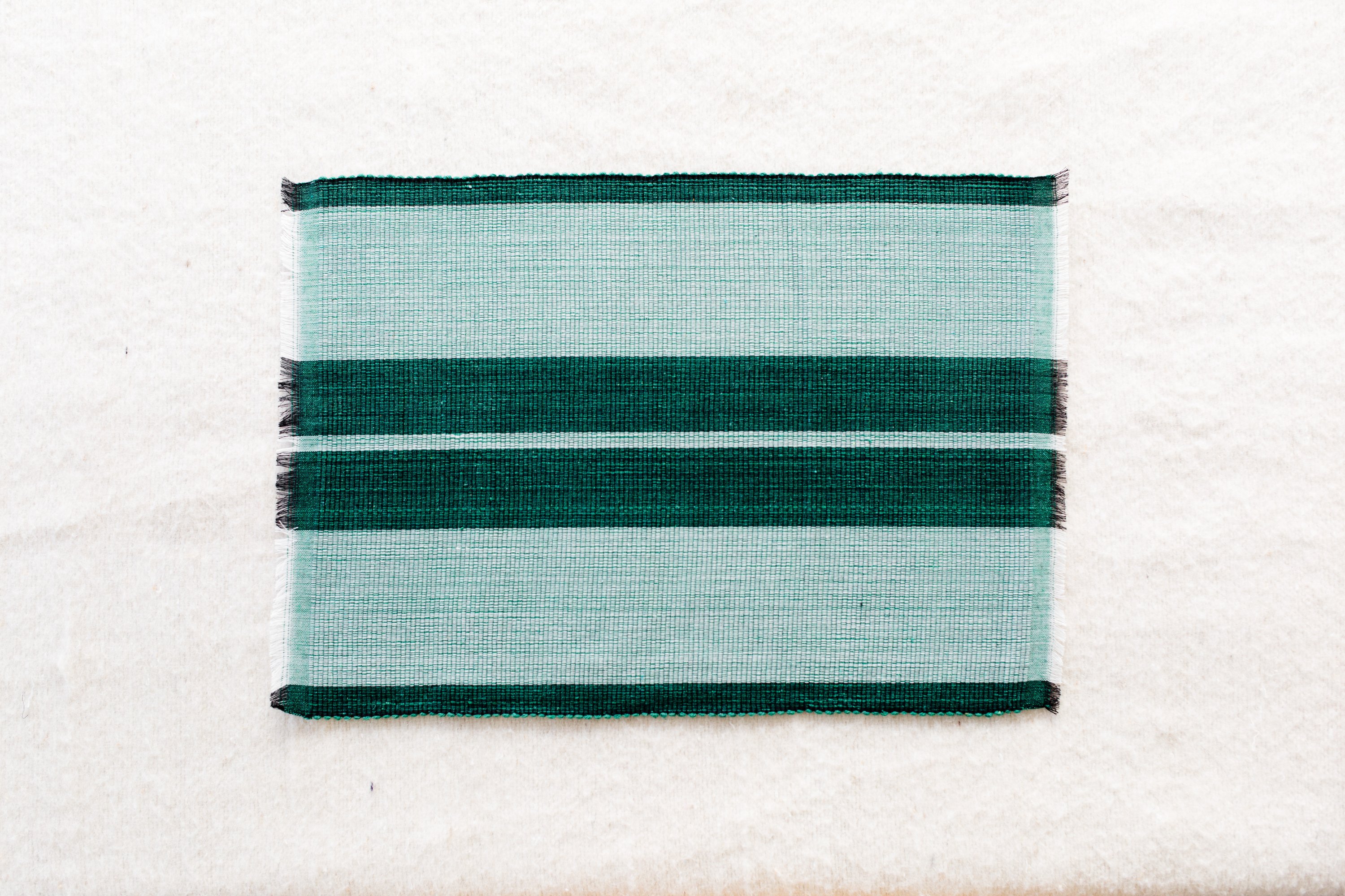 Handcrafted forrest green woven cotton dining placemat showcasing raised ribbed patterns, perfect for enhancing table settings.