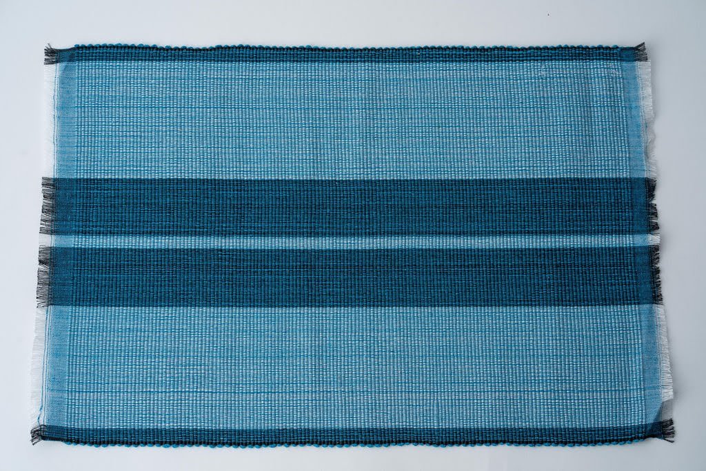 Ocean blue woven cotton dining placemat with raised ribbed patterns, handcrafted by local artisans.