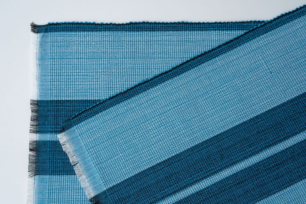 Ocean blue woven cotton dining placemat with raised ribbed patterns, handcrafted by local artisans.