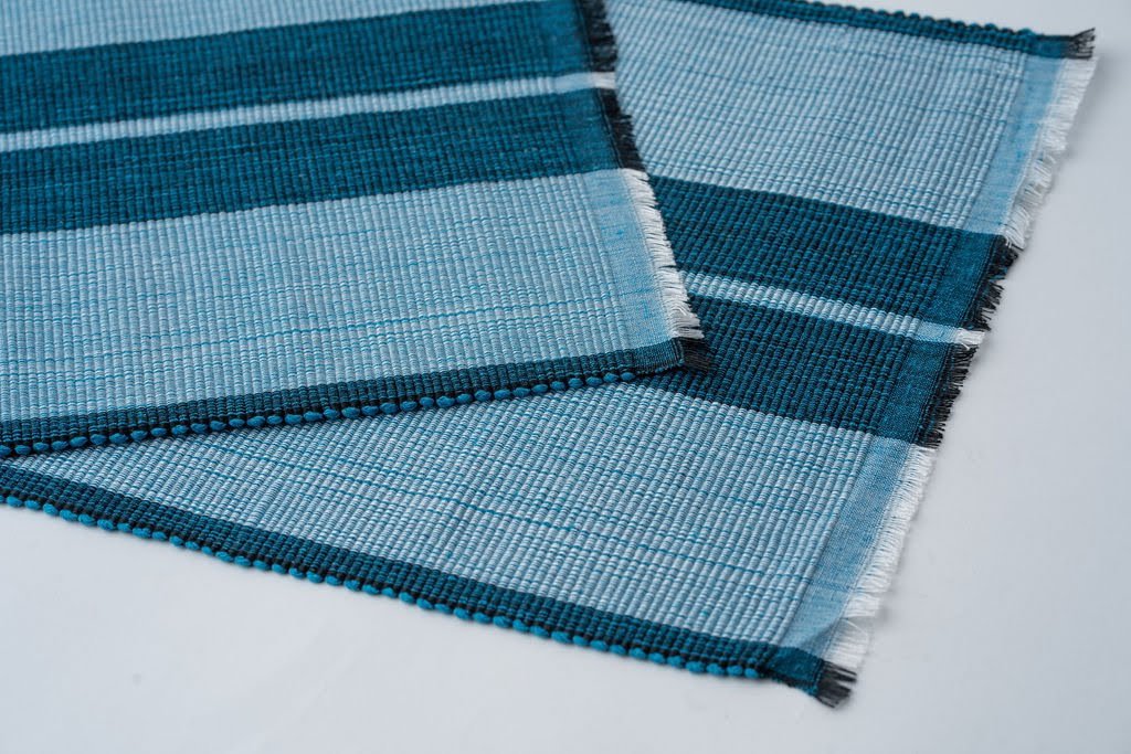 Ocean blue woven cotton dining placemat with raised ribbed patterns, handcrafted by local artisans.