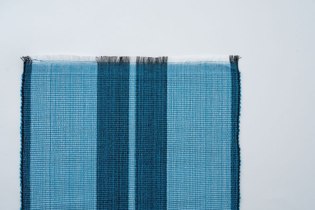 Ocean blue woven cotton dining placemat with raised ribbed patterns, handcrafted by local artisans.