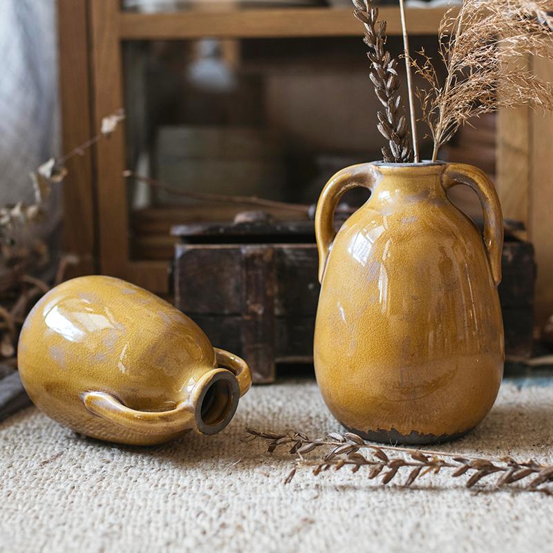 A vibrant yellow glazed ceramic vase with elegant handles, showcasing a unique handmade design.