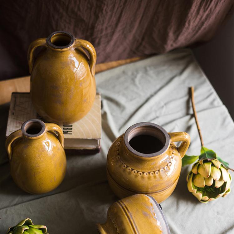 A vibrant yellow glazed ceramic vase with elegant handles, showcasing a unique handmade design.