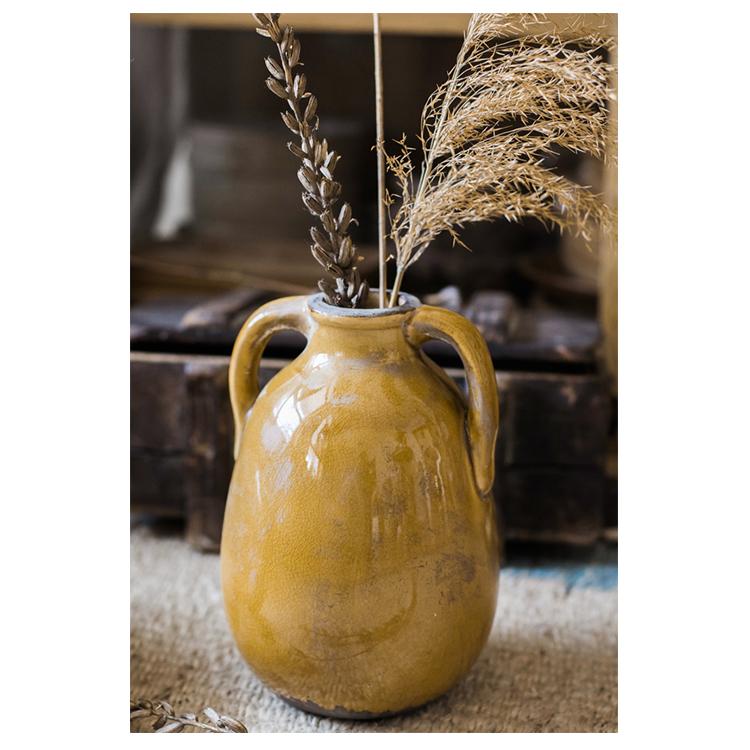 A vibrant yellow glazed ceramic vase with elegant handles, showcasing a unique handmade design.