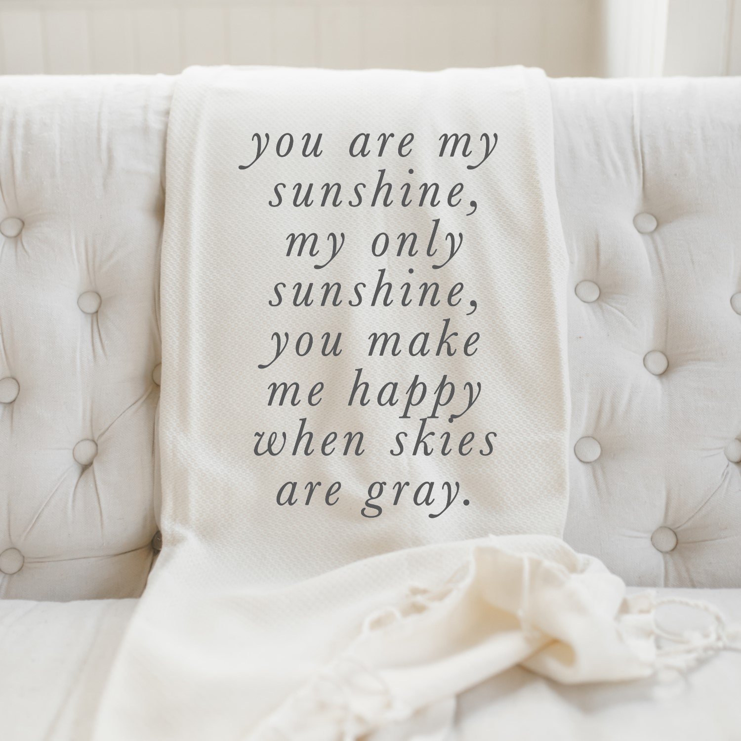 You Are My Sunshine Throw Blanket featuring unique calligraphy designs on organic cotton fabric, displayed elegantly on a couch.