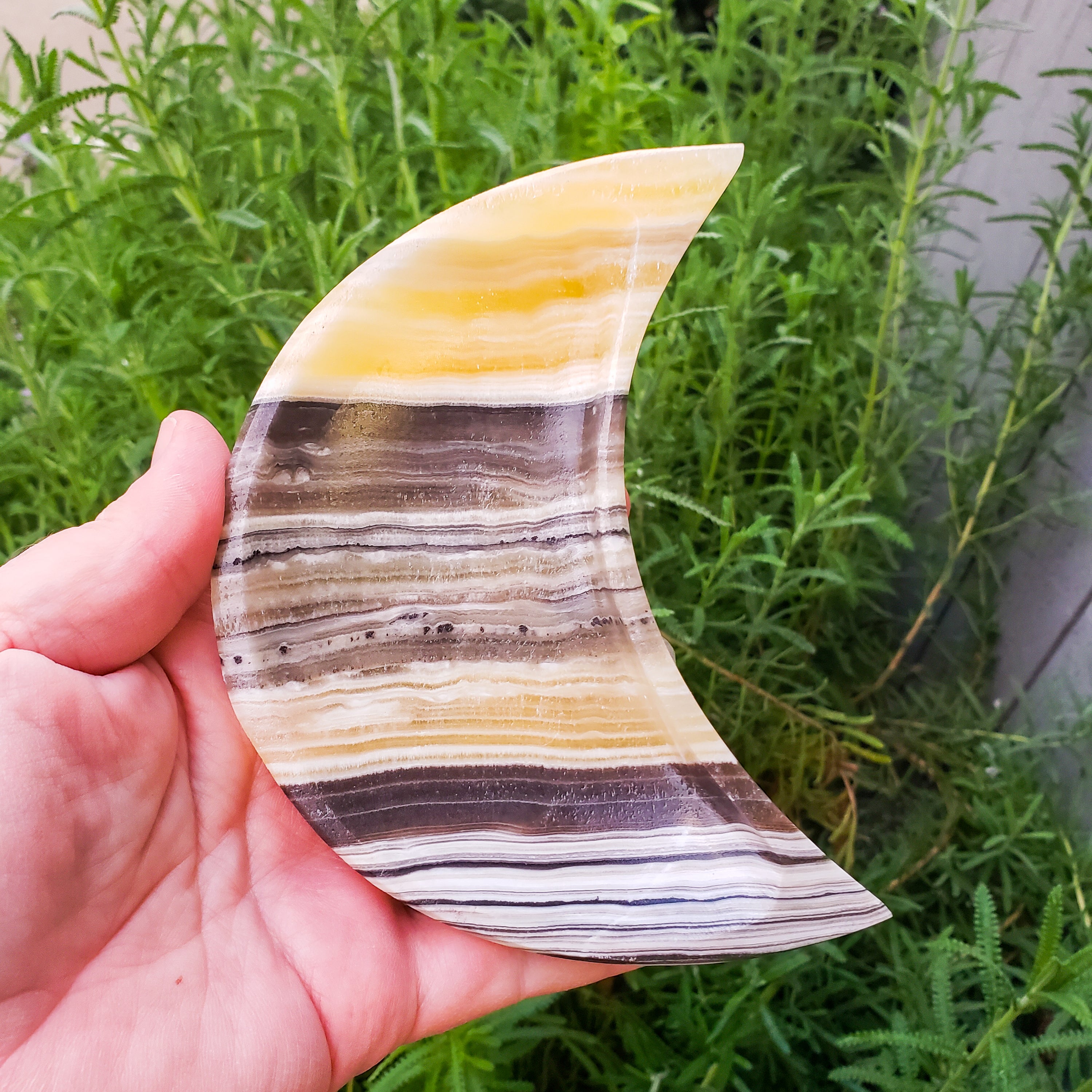 A beautifully crafted Zebra Onyx Moon Bowl featuring yellow, gray, white, and black bands, shaped like a crescent moon.