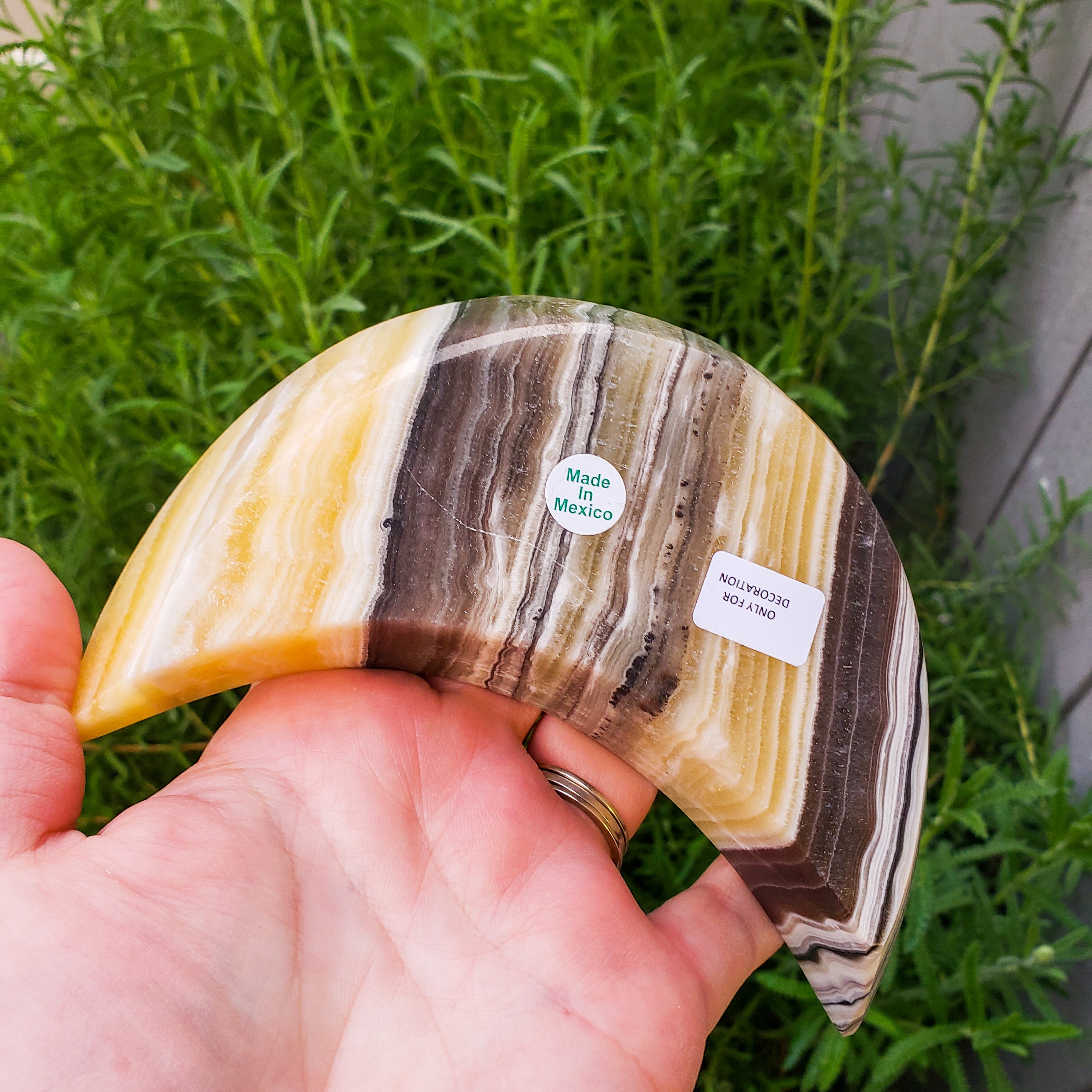 A beautifully crafted Zebra Onyx Moon Bowl featuring yellow, gray, white, and black bands, shaped like a crescent moon.