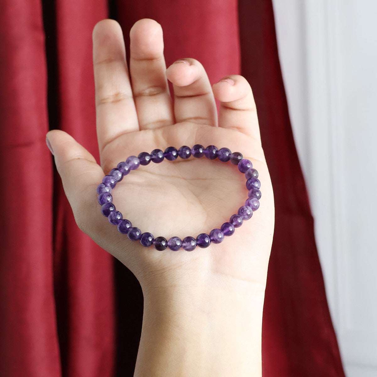 Amethyst Round Beads Bracelet showcasing natural purple crystals in various sizes, elegantly strung on an elastic band.