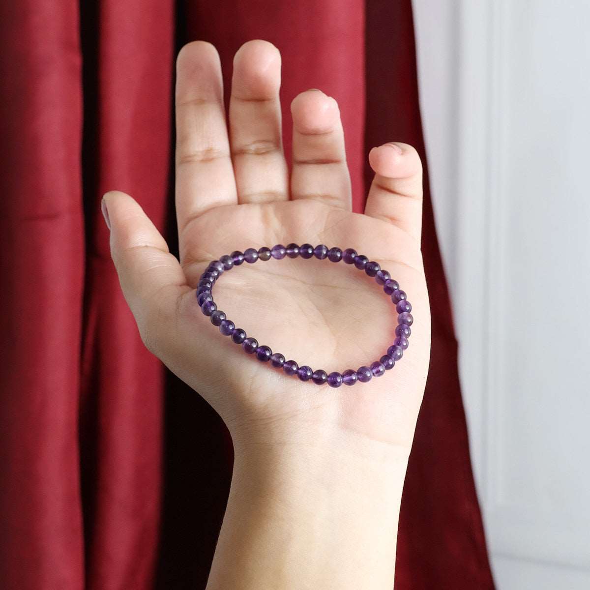 Amethyst Round Beads Bracelet showcasing natural purple crystals in various sizes, elegantly strung on an elastic band.