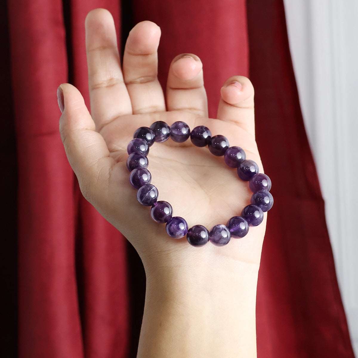 Amethyst Round Beads Bracelet showcasing natural purple crystals in various sizes, elegantly strung on an elastic band.