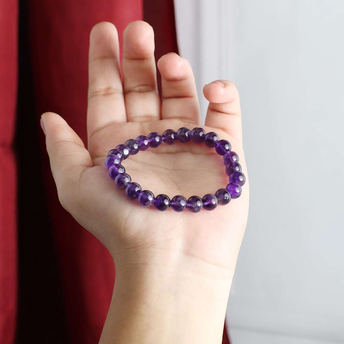 Amethyst Round Beads Bracelet showcasing natural purple crystals in various sizes, elegantly strung on an elastic band.