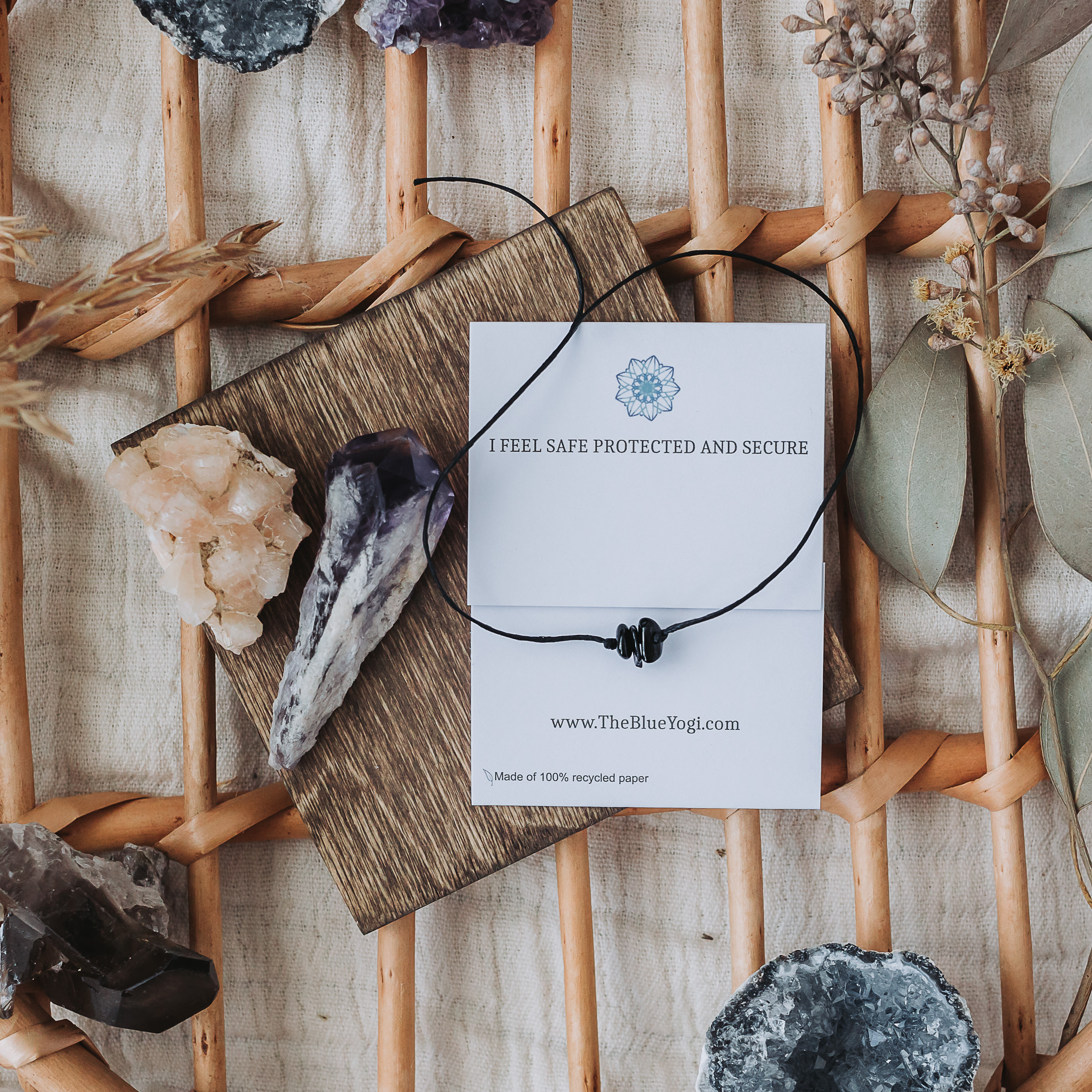 A handcrafted Black Tourmaline Band with a tie closure, featuring unique natural gemstones and a watercolor Mandala art card.