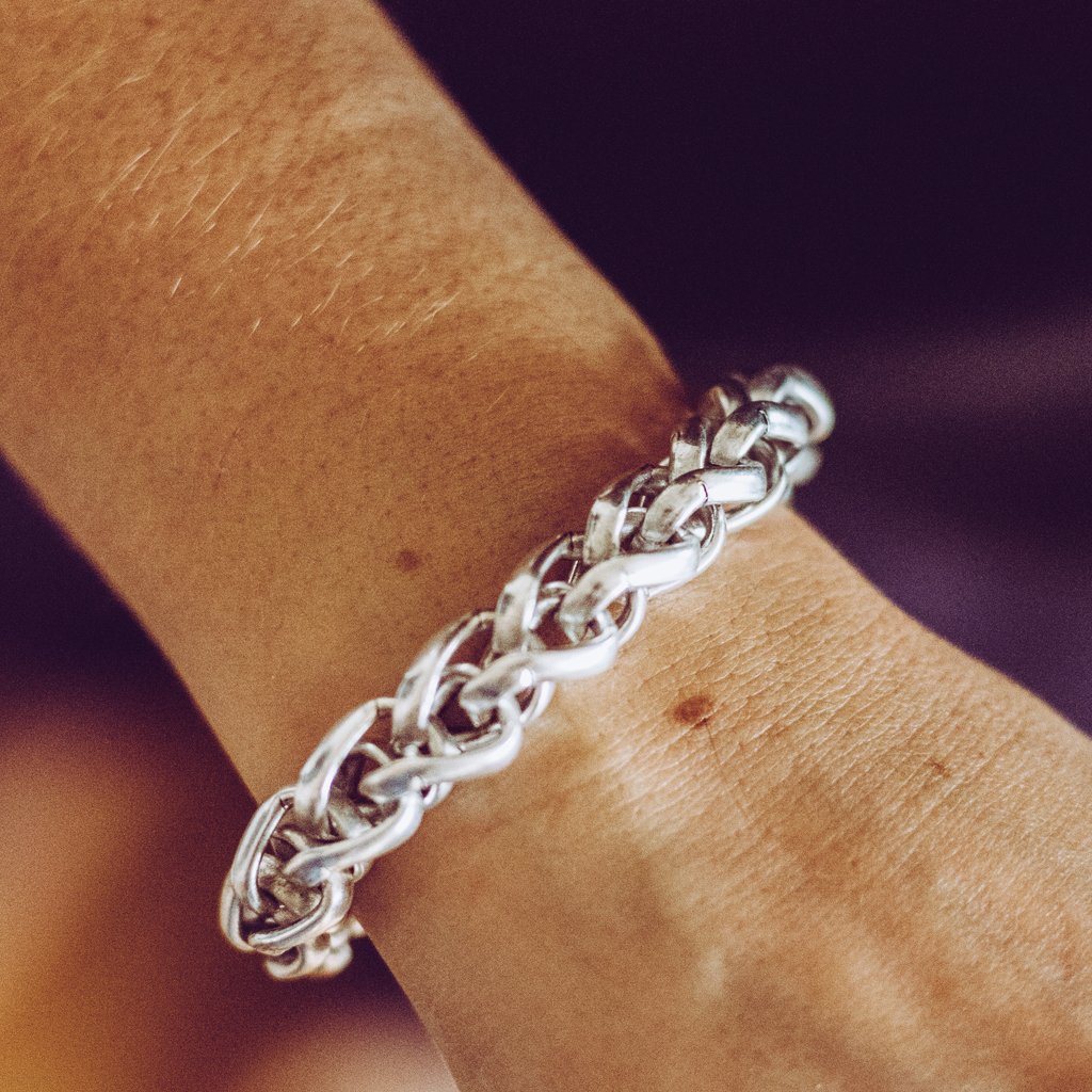 A stylish braided link bracelet made of pewter with gold or silver plating, featuring interlocked links and a lobster clasp.