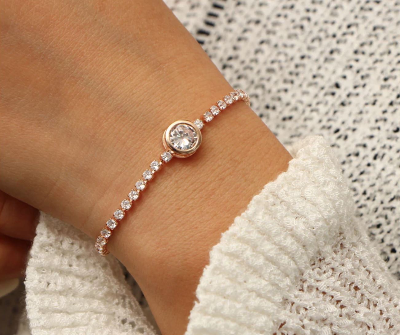 A beautiful Crystal Tennis Bracelet featuring sparkling cubic zirconia stones, available in rose gold and silver finishes, showcasing its adjustable design.