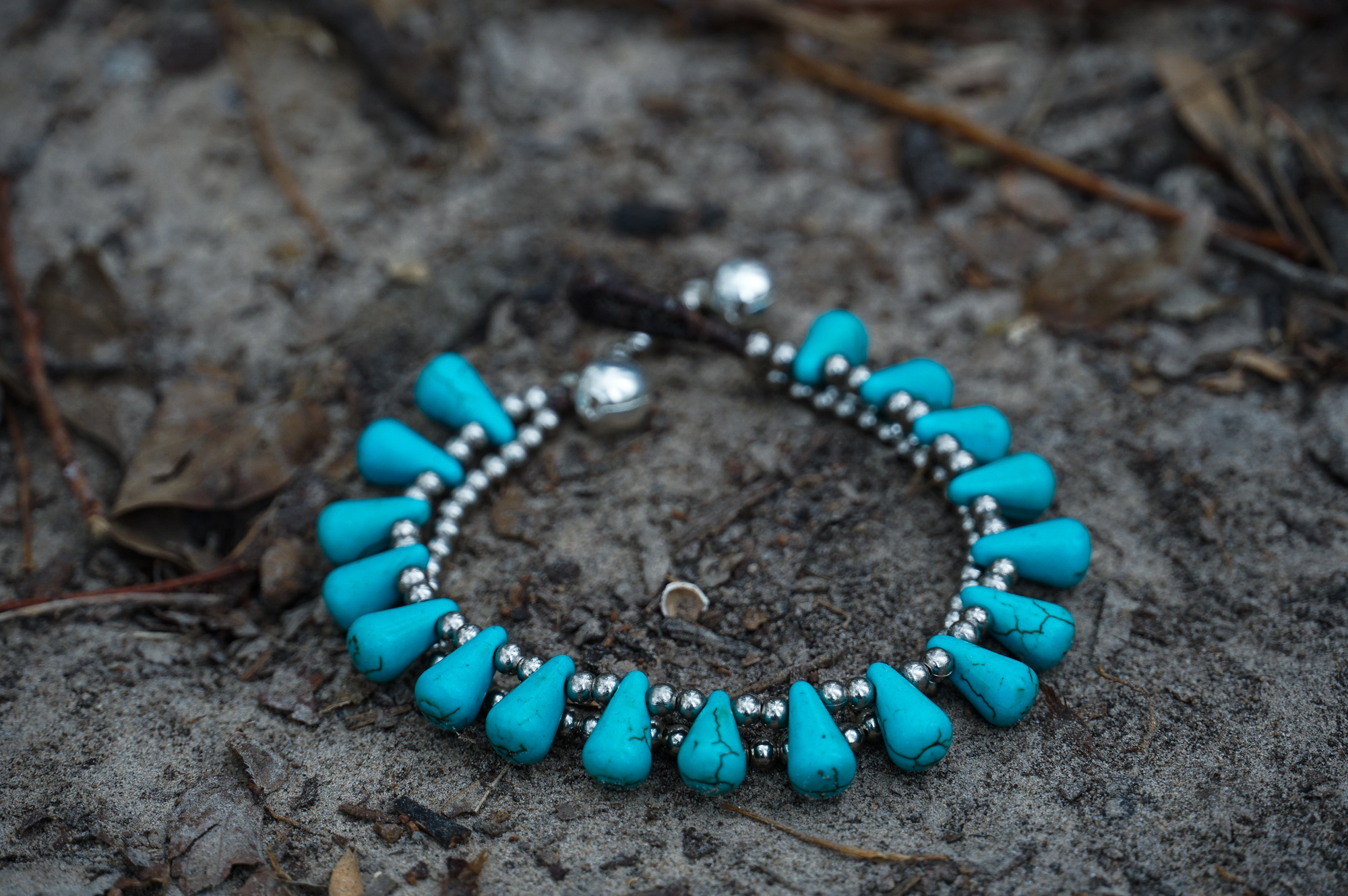 A pair of handmade double stranded boho silver bracelets featuring natural stones and pressed cotton cord, showcasing a chic and unique design.