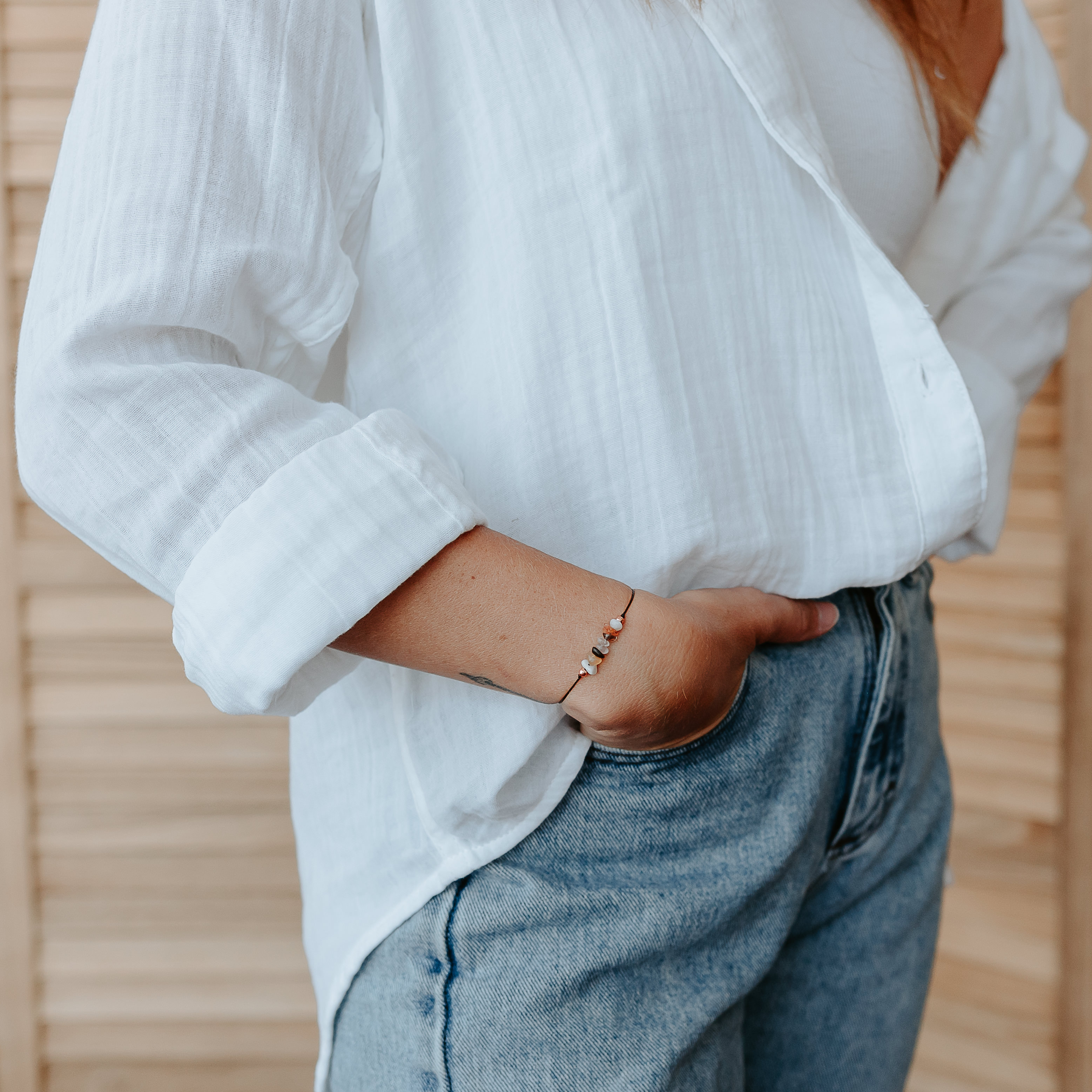 A handcrafted Fertility Bracelet made of natural gemstones on a hemp cord, featuring a tie closure and a Mandala art card with healing properties.