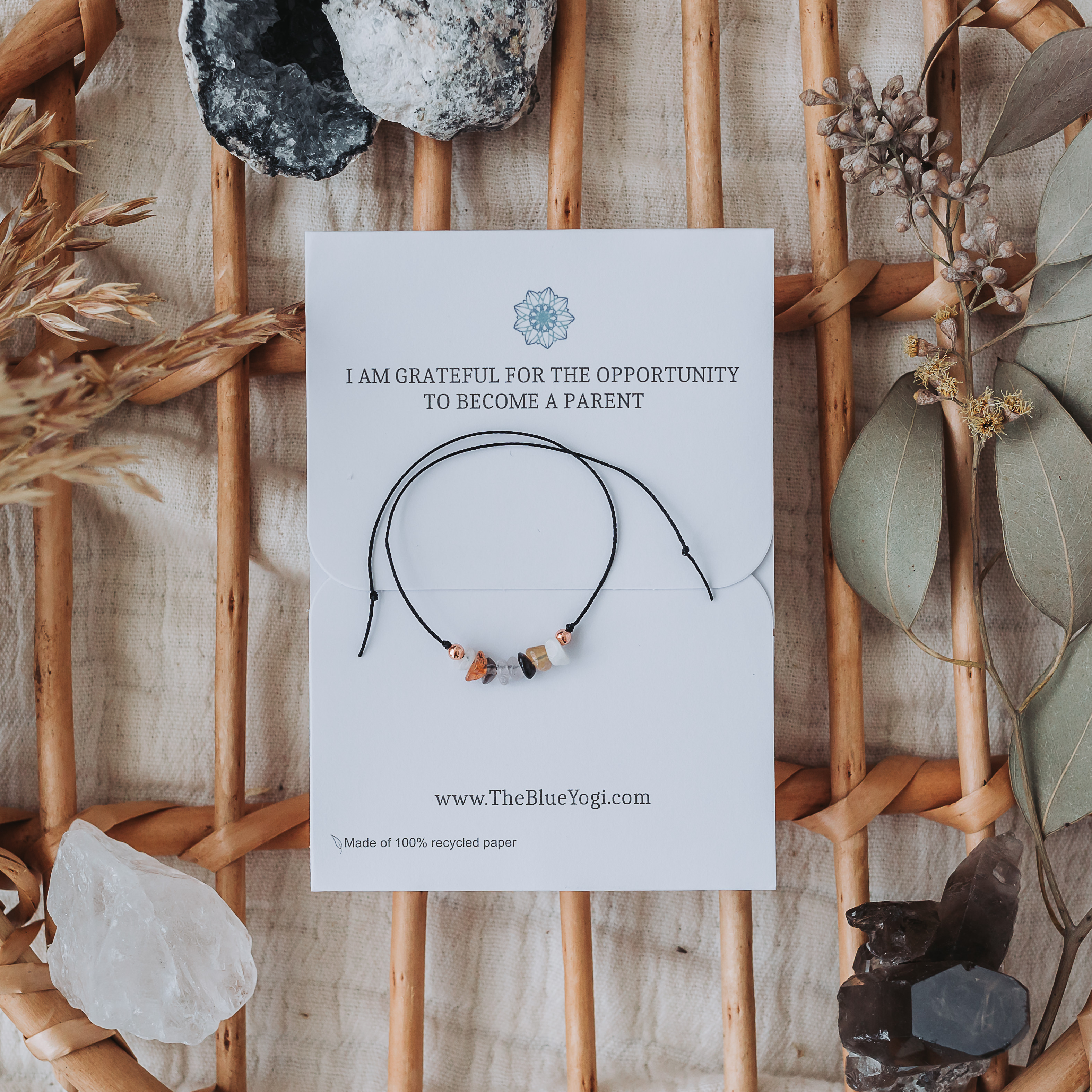 A handcrafted Fertility Bracelet made of natural gemstones on a hemp cord, featuring a tie closure and a Mandala art card with healing properties.