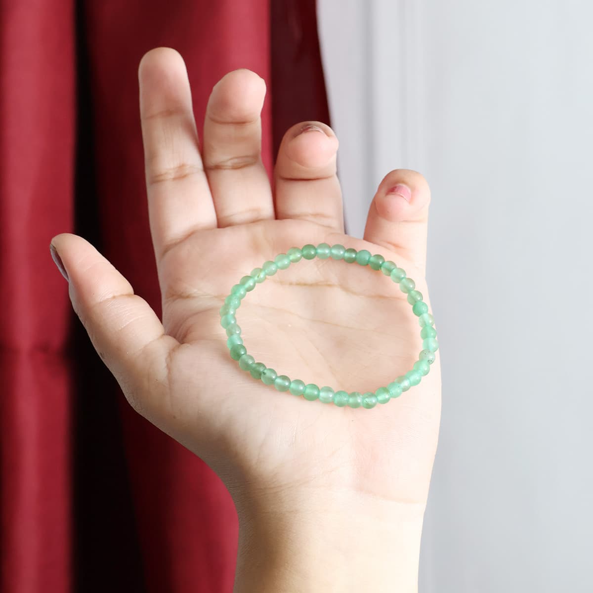 A close-up view of a Green Aventurine Round Beads Bracelet showcasing its natural green stones and elastic design.