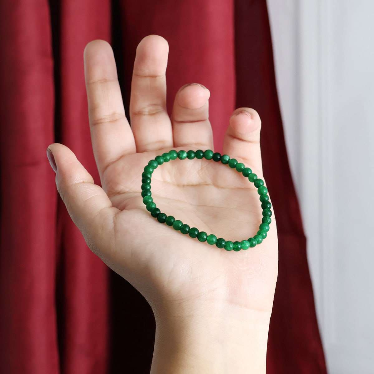 A beautiful Green Jade Round Beads Bracelet showcasing natural jade beads in various sizes, elegantly strung on an elastic band.