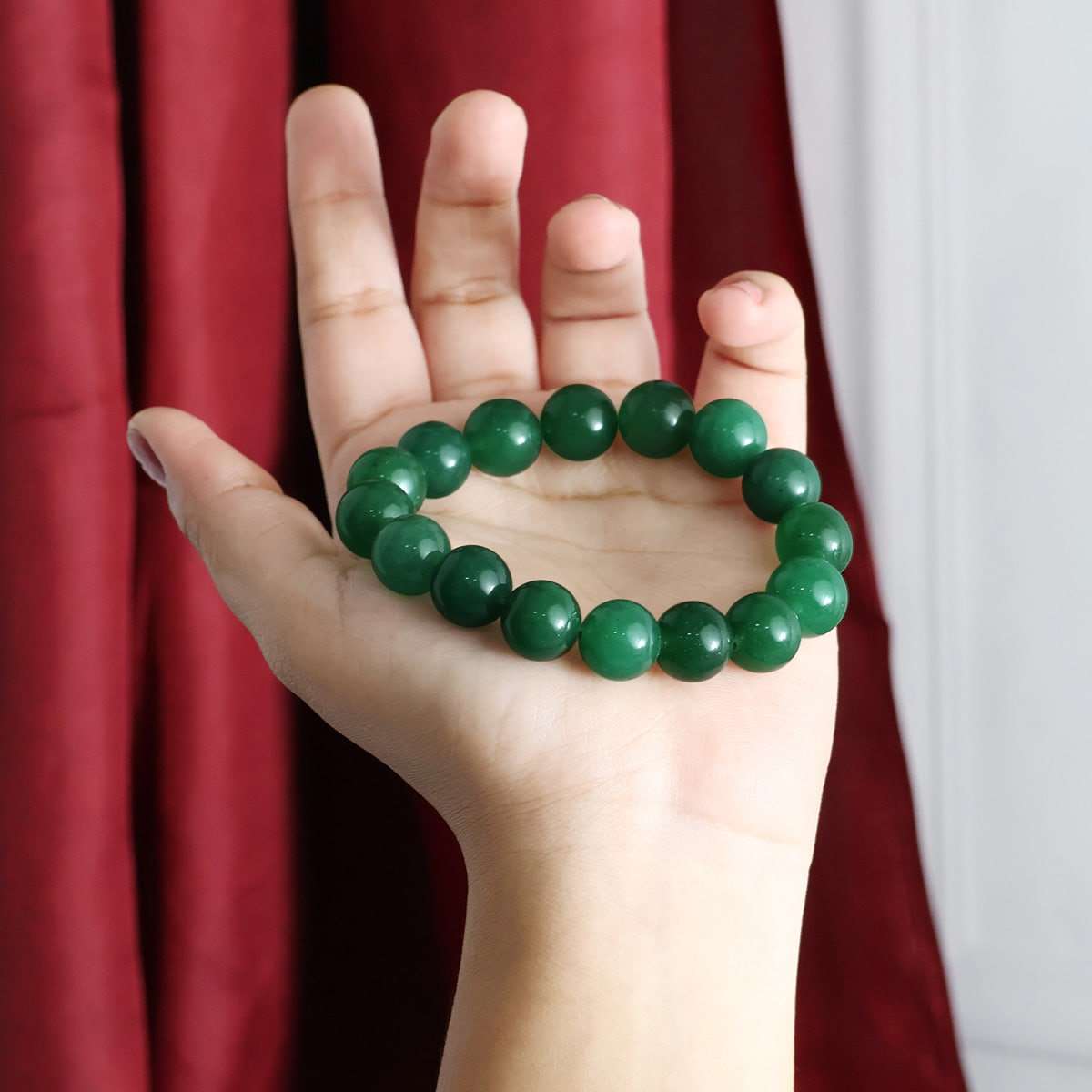 A beautiful Green Jade Round Beads Bracelet showcasing natural jade beads in various sizes, elegantly strung on an elastic band.