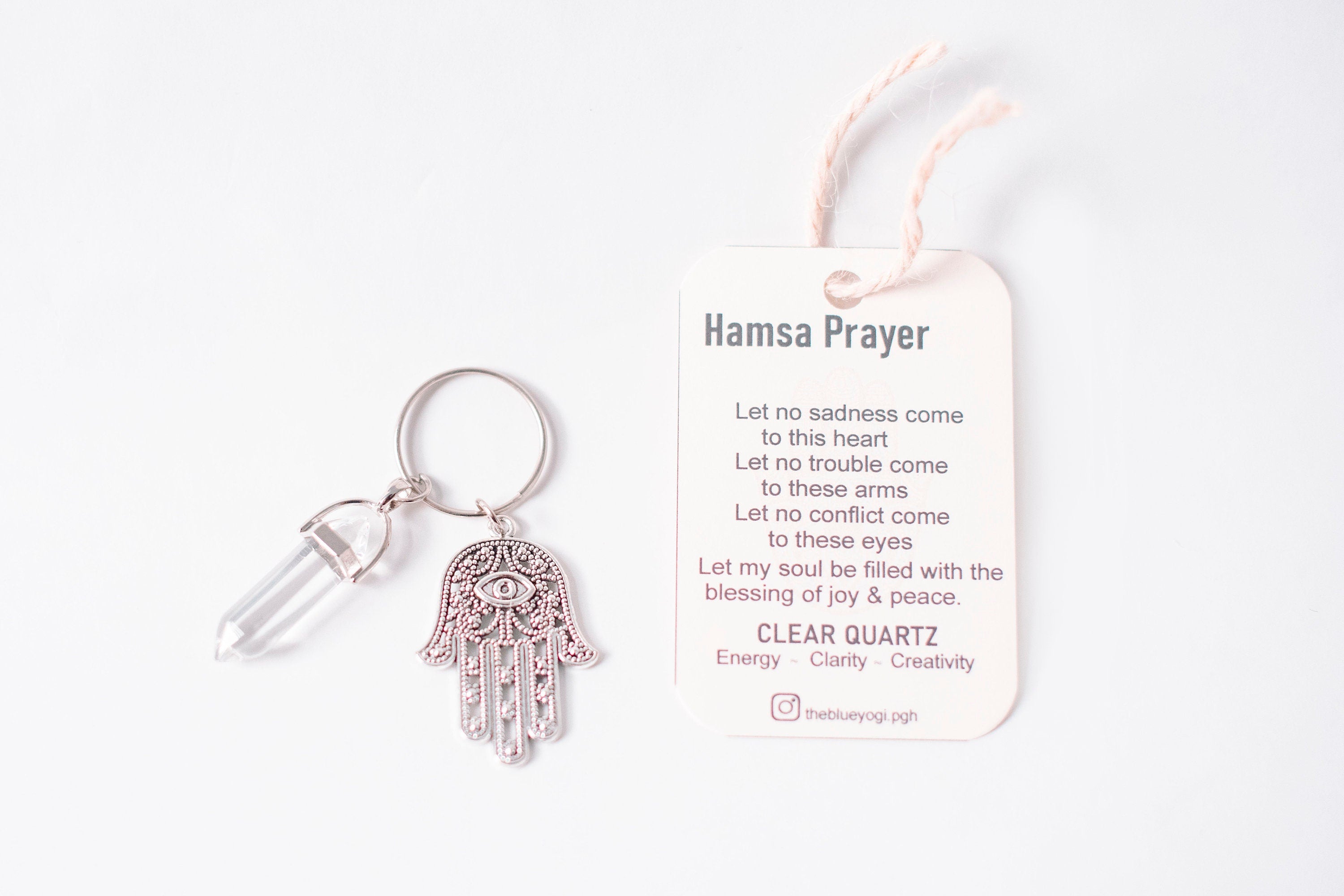 Hamsa & Clear Quartz Key Chain featuring an intricate Hamsa design and a Clear Quartz stone, accompanied by a Hamsa Prayer Card.