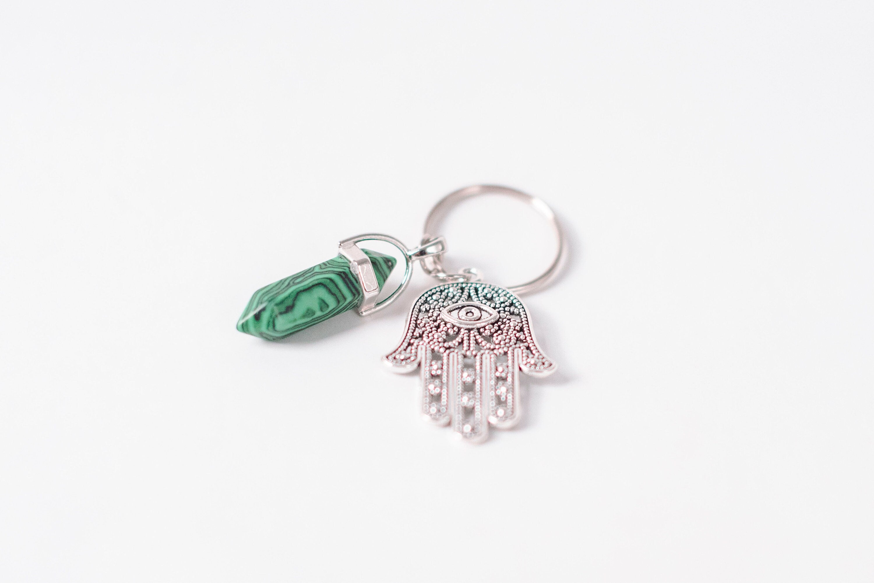 A beautifully crafted Hamsa & Malachite Key Chain featuring a hexagonal malachite stone and a protective Hamsa charm.