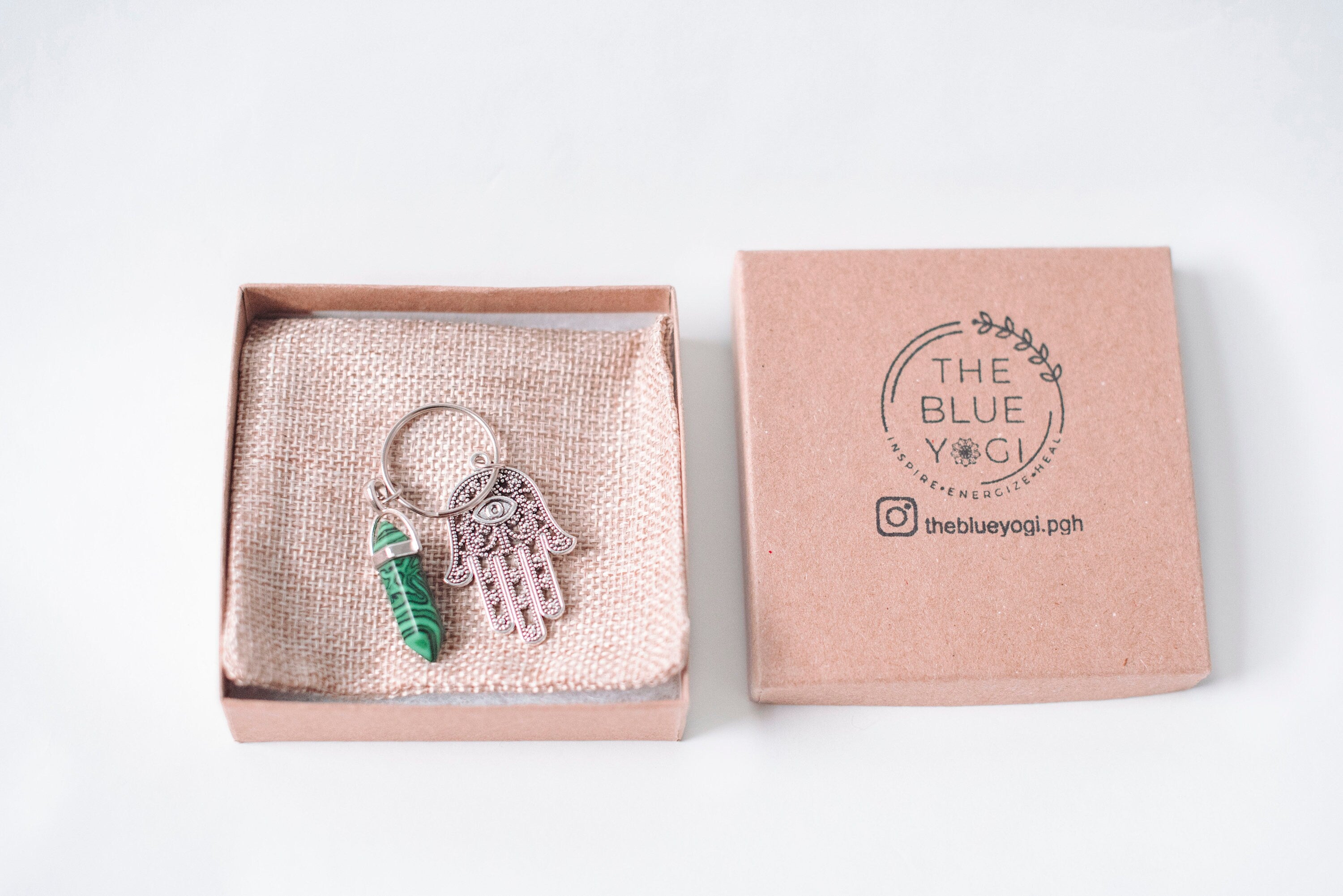 A beautifully crafted Hamsa & Malachite Key Chain featuring a hexagonal malachite stone and a protective Hamsa charm.