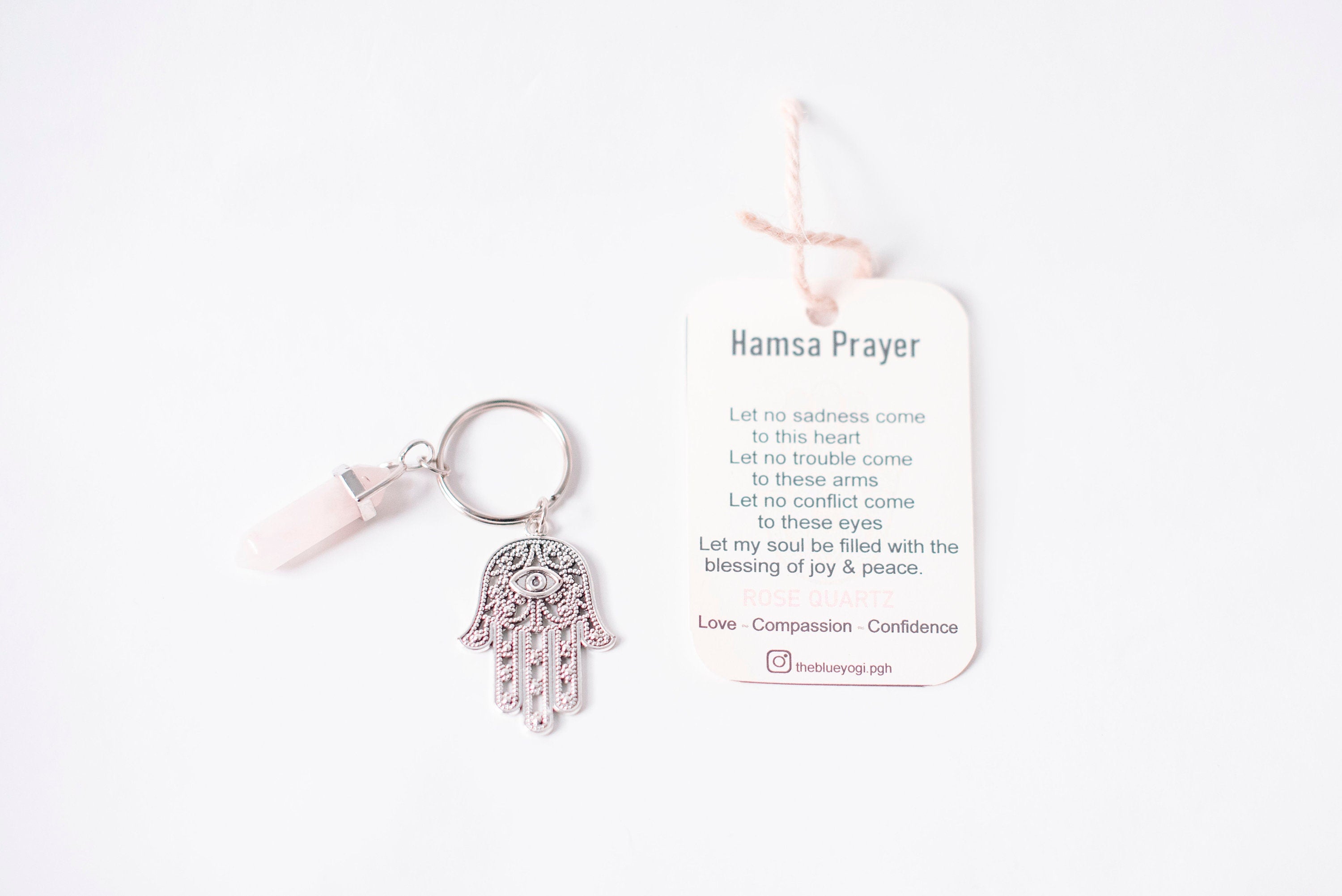 A stylish Hamsa & Rose Quartz keychain featuring a hexagonal rose quartz stone and a Hamsa charm, perfect for spiritual protection.