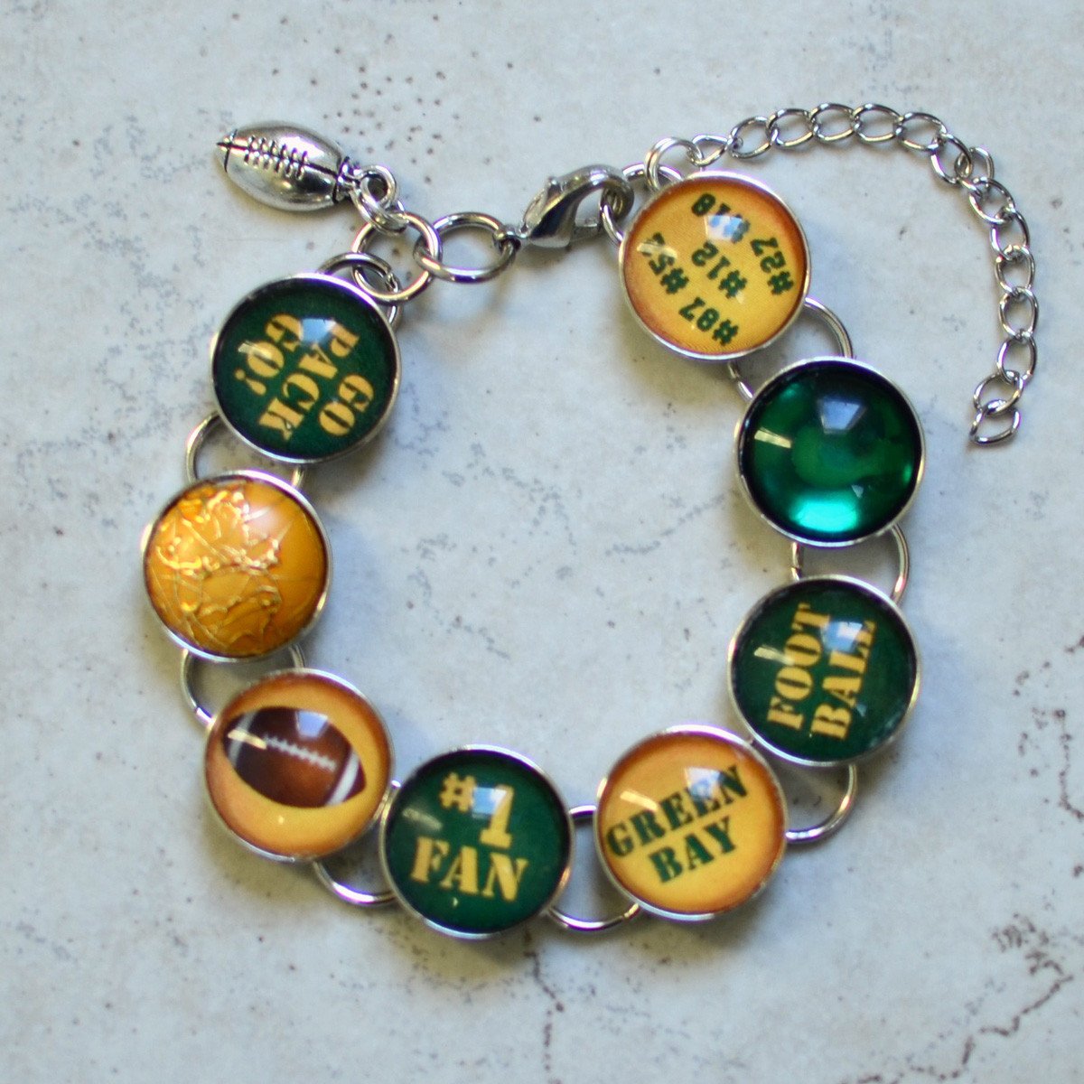 Handmade charm bracelet featuring Green Bay Packers charms and a dangling football charm, showcasing vibrant colors and unique designs.