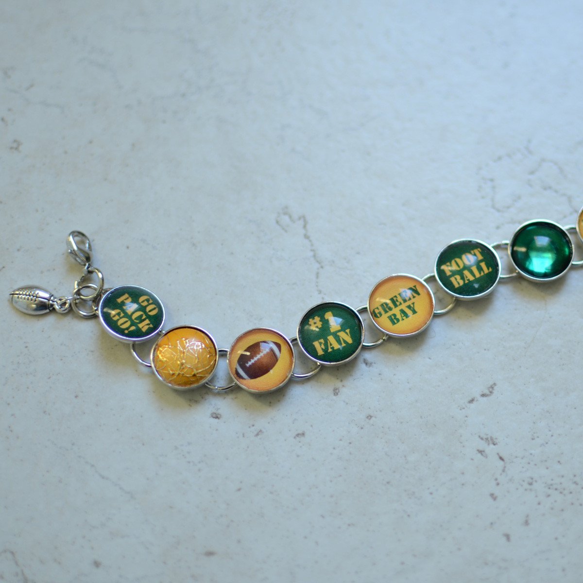 Handmade charm bracelet featuring Green Bay Packers charms and a dangling football charm, showcasing vibrant colors and unique designs.