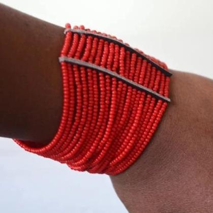 A vibrant Maasai African Beaded Cuff Spiral Arm Bracelet featuring red African beads and leather, showcasing intricate craftsmanship.